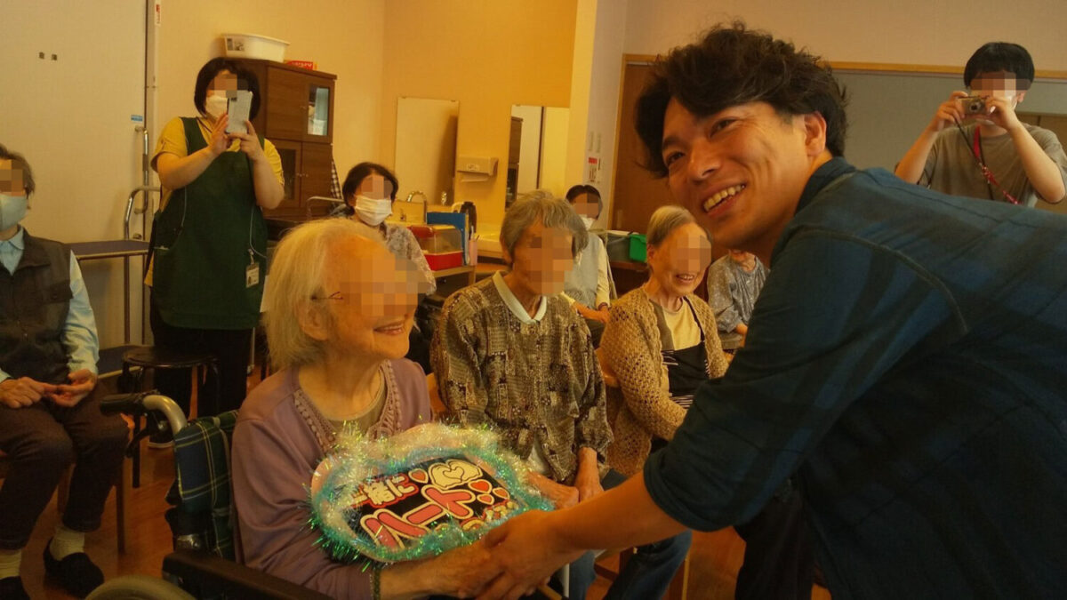 介護施設のライブで利用者と交流をする尾上明範（おのえ・あきのり）さん（右）